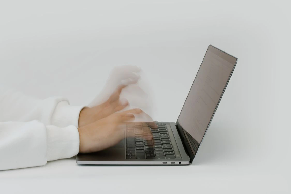 Tangan mengetik di keyboard laptop dengan tampilan terkait keamanan siber