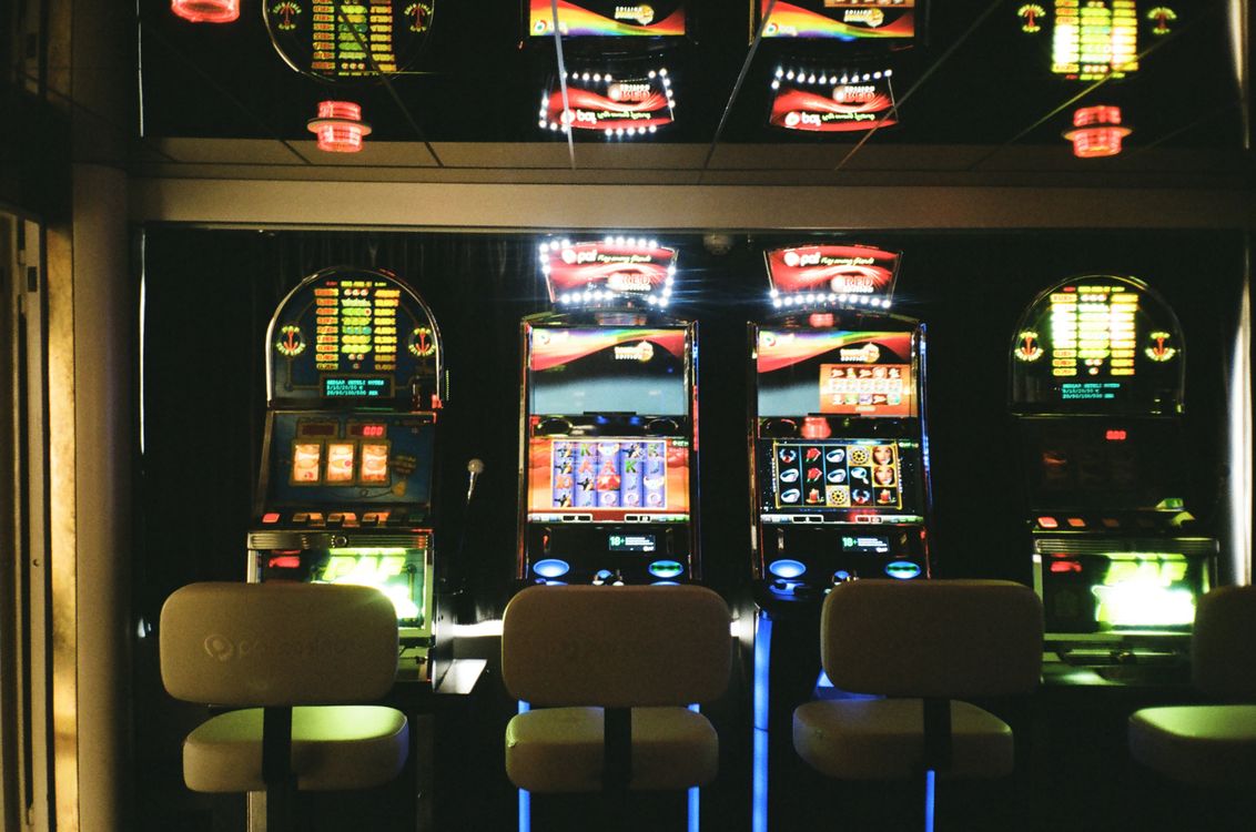 Deretan mesin slot di dalam kasino dengan pencahayaan redup dan suasana permainan