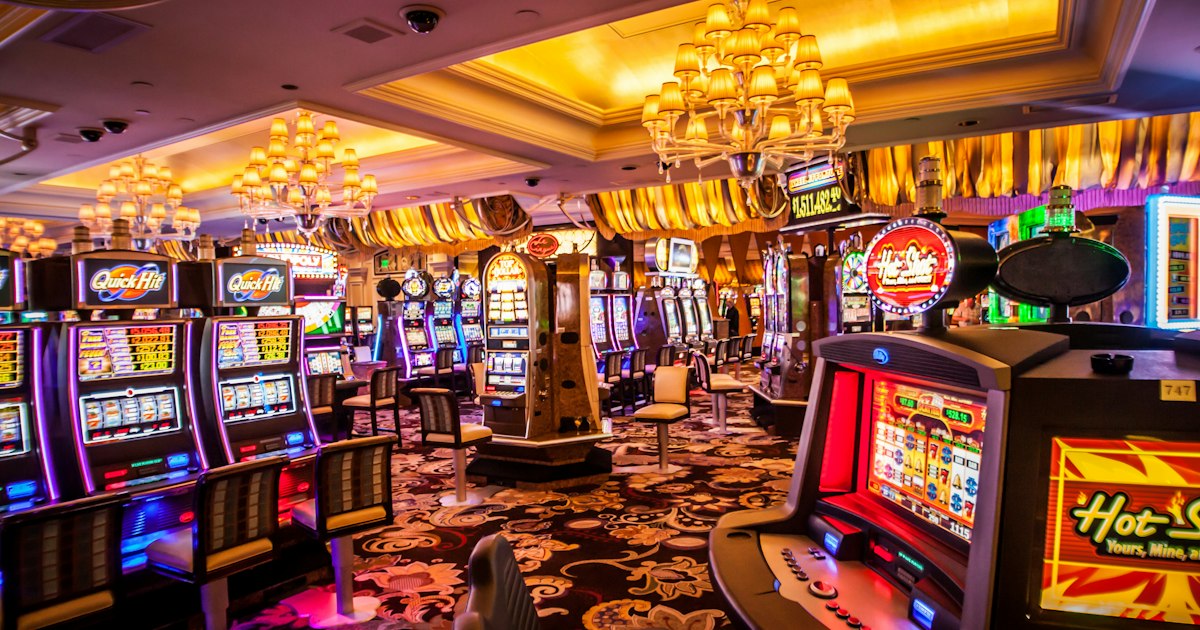 Deretan mesin slot dengan lampu menyala di dalam kasino