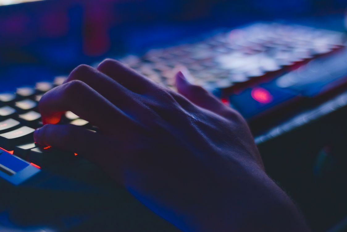 Seseorang mengetik di keyboard komputer dalam pencahayaan redup