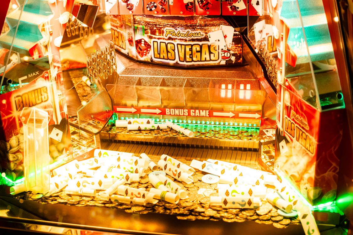 Mesin slot kasino berwarna-warni dengan layar jackpot dan lampu neon bertema Las Vegas