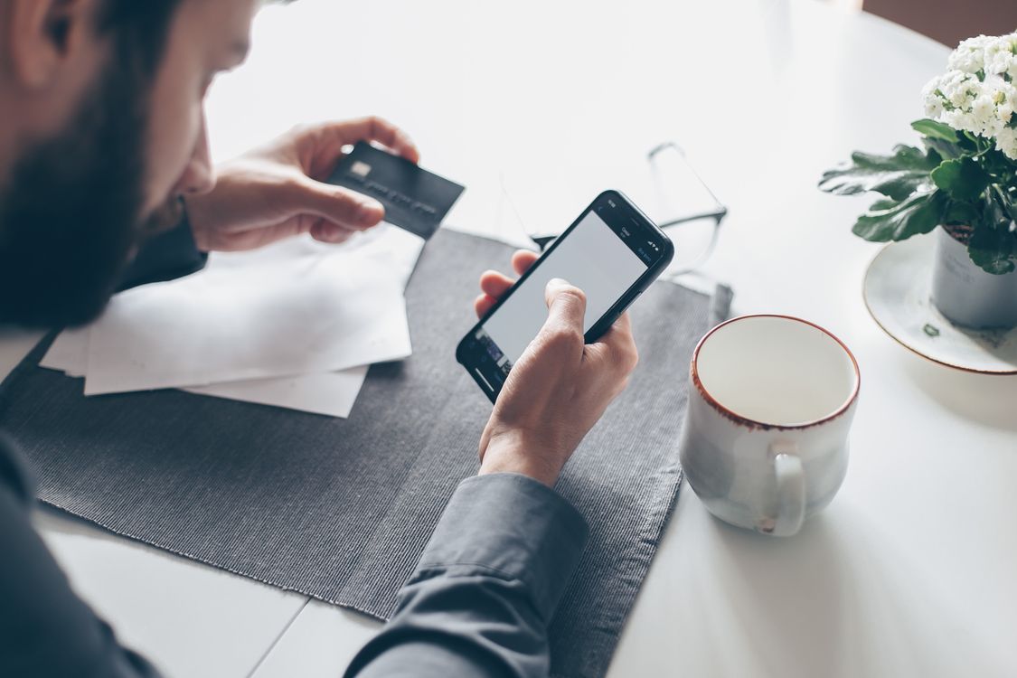Pria memegang smartphone dan kartu untuk transaksi pembayaran online