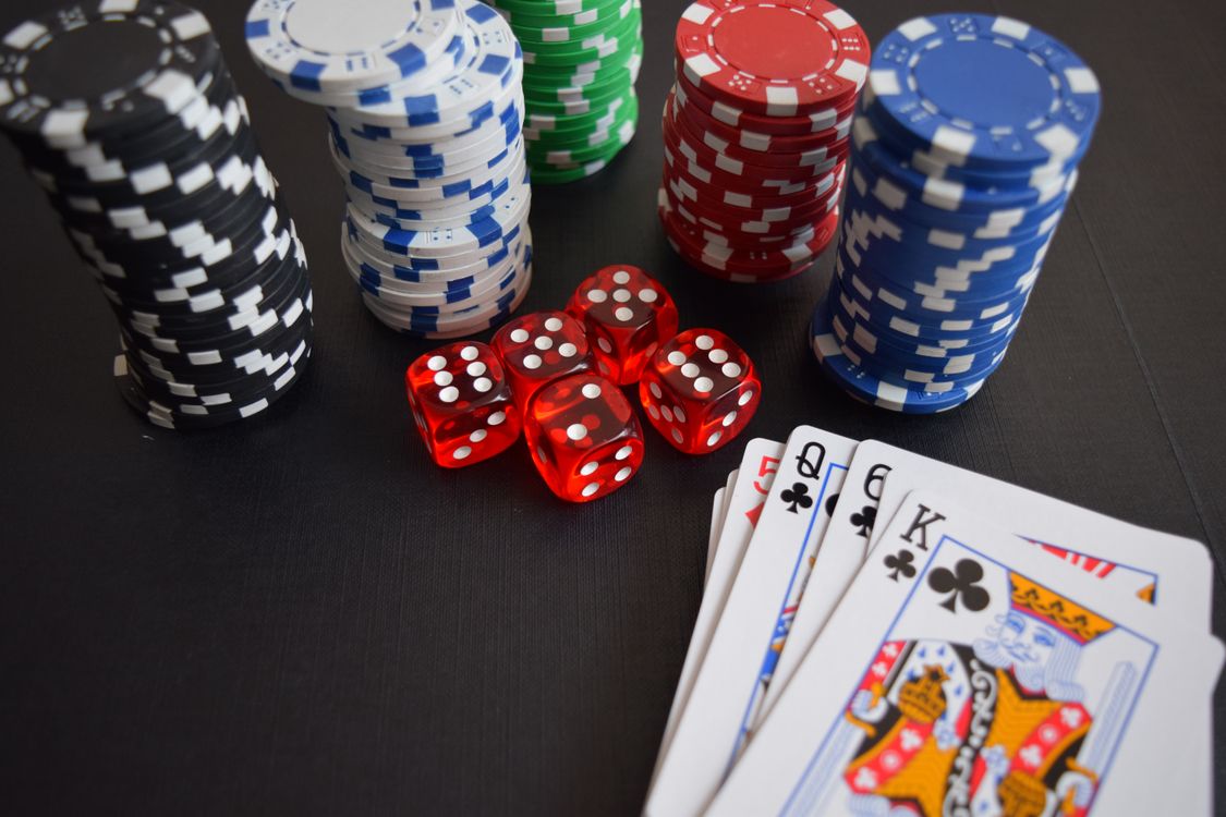 Chip kasino berwarna dan kartu remi tersusun di atas meja perjudian